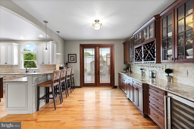 indoor dry bar featuring wine cooler, light wood finished floors, decorative backsplash, decorative light fixtures, and recessed lighting