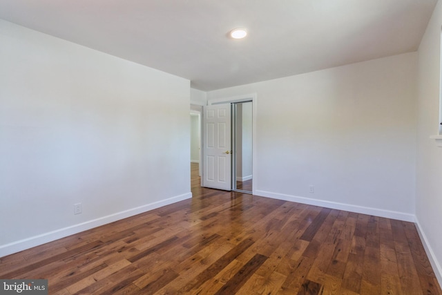 spare room with baseboards and wood finished floors