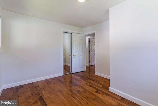 unfurnished bedroom featuring baseboards, a closet, and wood finished floors