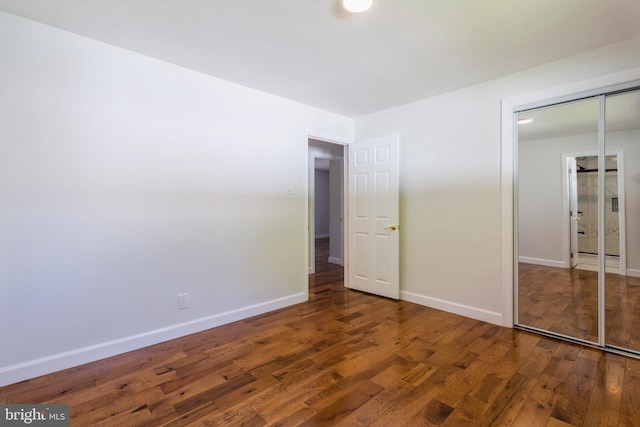 unfurnished bedroom featuring baseboards, a closet, and wood finished floors
