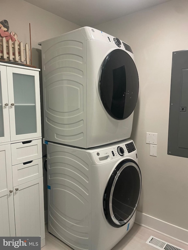 3 Talbot Ave, Cambridge, MD 21613 - laundry room featuring stacked washer and clothes dryer, cabinet space, electric panel, and baseboards