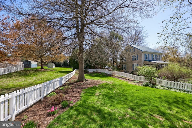 view of yard featuring a fenced backyard, a shed, and an outbuilding