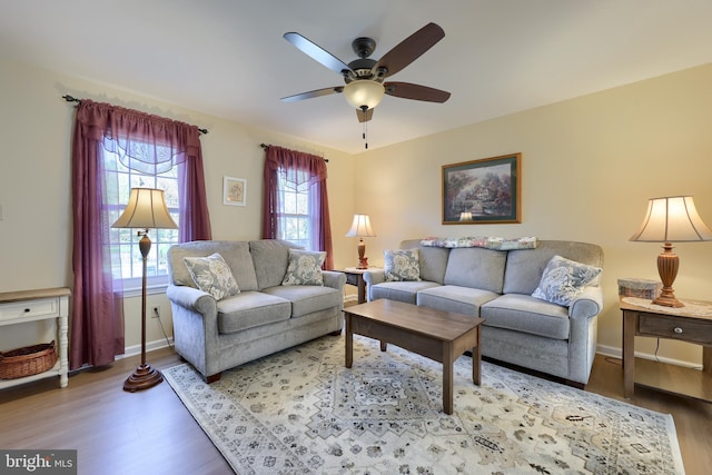 living area featuring baseboards, a ceiling fan, and wood finished floors