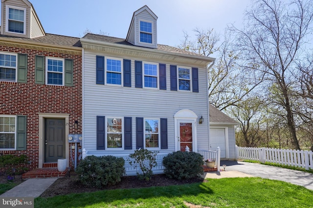 townhome / multi-family property with fence, driveway, and a garage