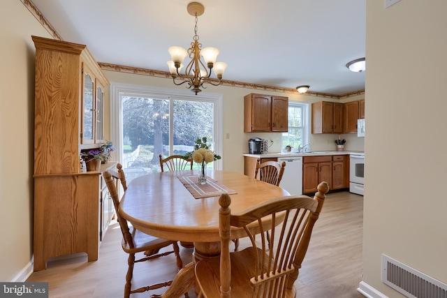 dining space featuring light wood finished floors, a chandelier, and visible vents