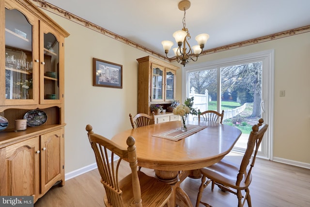 dining room with baseboards, light wood-type flooring, and a chandelier