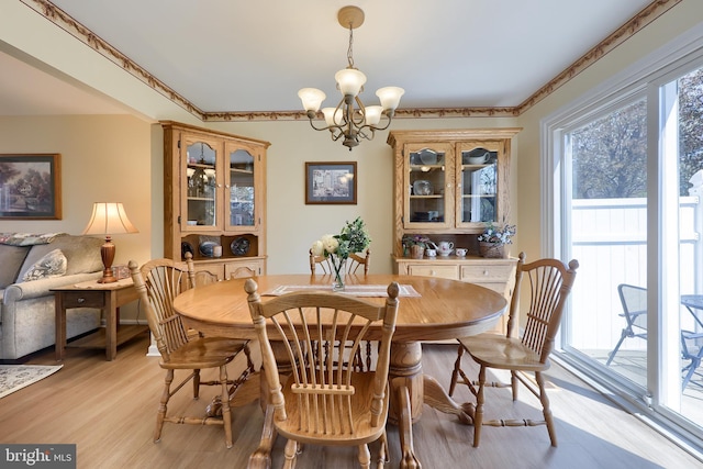 dining space featuring crown molding, a chandelier, and light wood finished floors