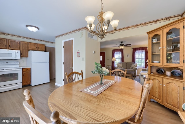 dining space featuring ceiling fan with notable chandelier and light wood-style flooring