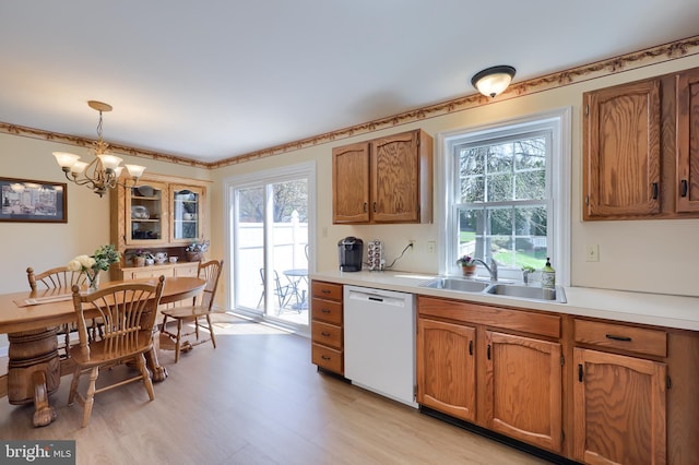 kitchen with hanging light fixtures, dishwasher, a sink, light countertops, and a chandelier