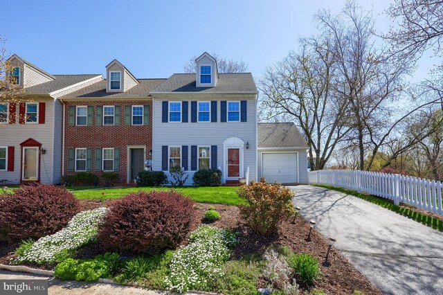 view of front facade featuring fence, a garage, and aphalt driveway