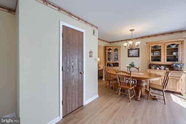 dining room featuring baseboards, light wood finished floors, and a notable chandelier