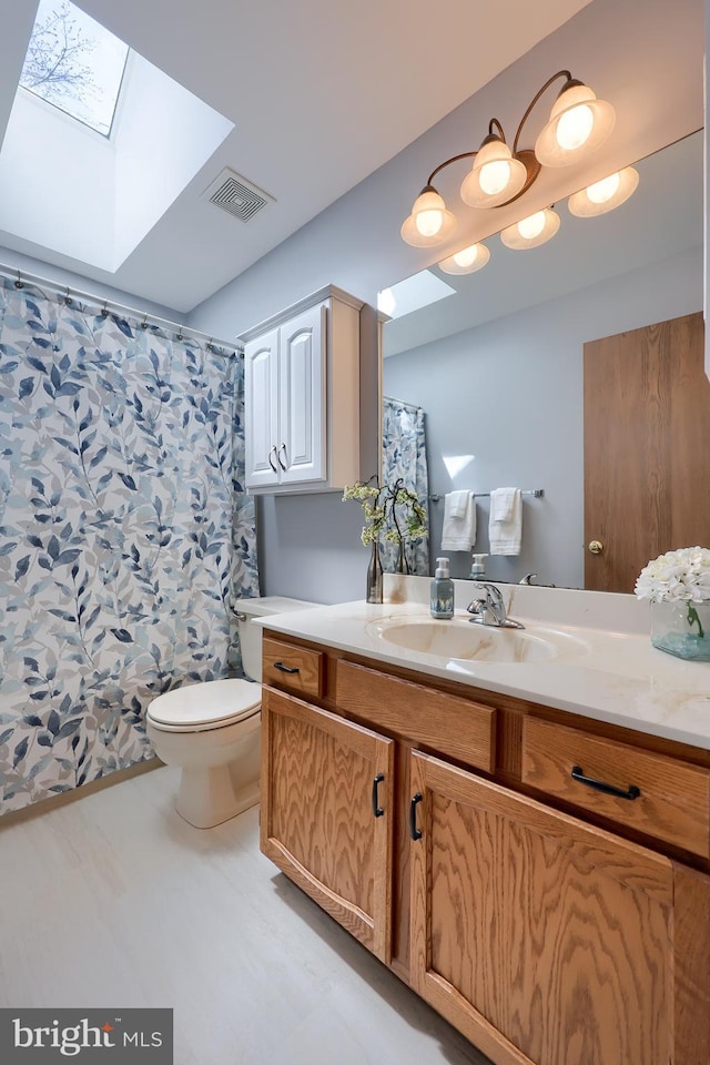 bathroom featuring visible vents, vanity, toilet, a shower with curtain, and a skylight