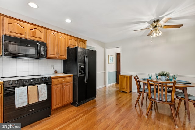 kitchen featuring ceiling fan, backsplash, light countertops, black appliances, and light wood-style flooring