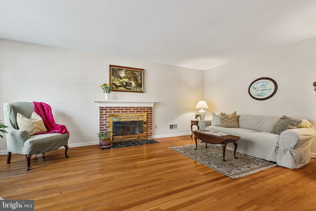 living area with baseboards, visible vents, and wood finished floors