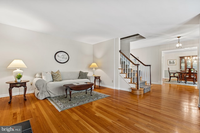 living room featuring baseboards, an inviting chandelier, wood finished floors, and stairway