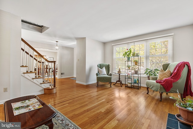 sitting room with stairs, baseboards, and wood finished floors