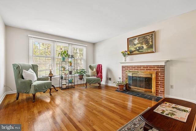 living area featuring baseboards, a fireplace, and wood finished floors