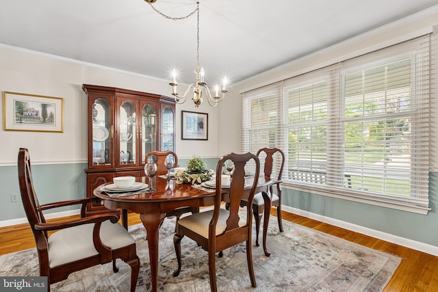 dining area featuring baseboards, a notable chandelier, ornamental molding, and wood finished floors