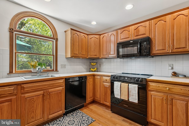 kitchen featuring light countertops, a sink, black appliances, and light wood-type flooring