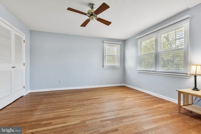unfurnished bedroom with a ceiling fan, baseboards, light wood finished floors, and a closet