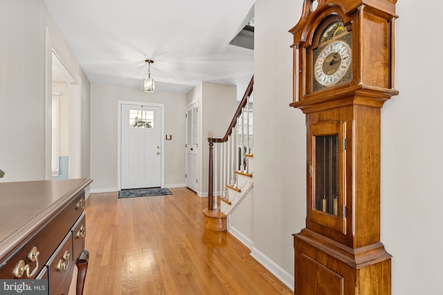 entrance foyer featuring baseboards, light wood-style flooring, and stairs