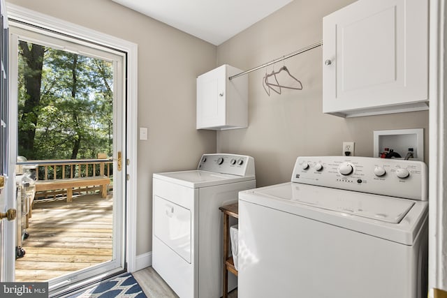laundry area with separate washer and dryer, light wood-style flooring, and cabinet space