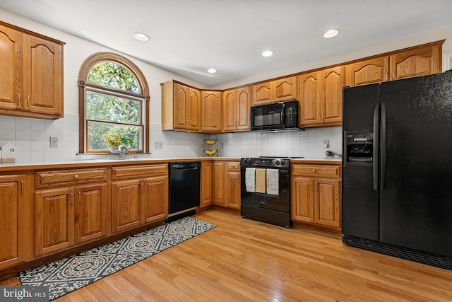kitchen featuring brown cabinetry, black appliances, and light wood-type flooring
