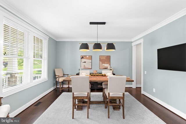 dining room with dark wood-style floors, visible vents, and ornamental molding