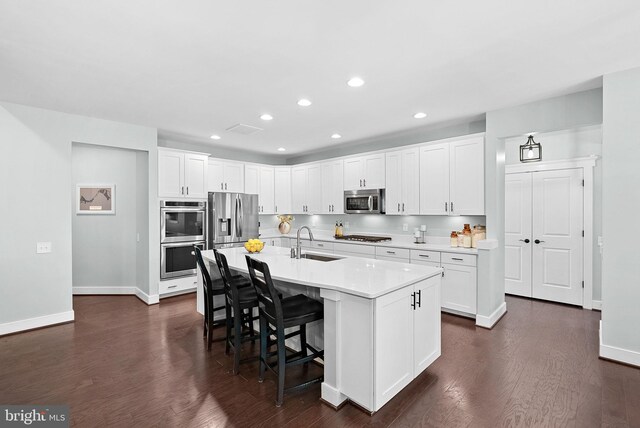 kitchen with a sink, appliances with stainless steel finishes, baseboards, and a breakfast bar