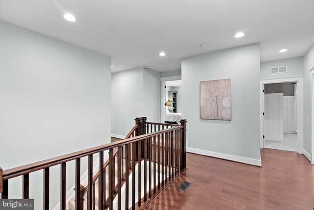 hallway featuring visible vents, recessed lighting, wood finished floors, and an upstairs landing