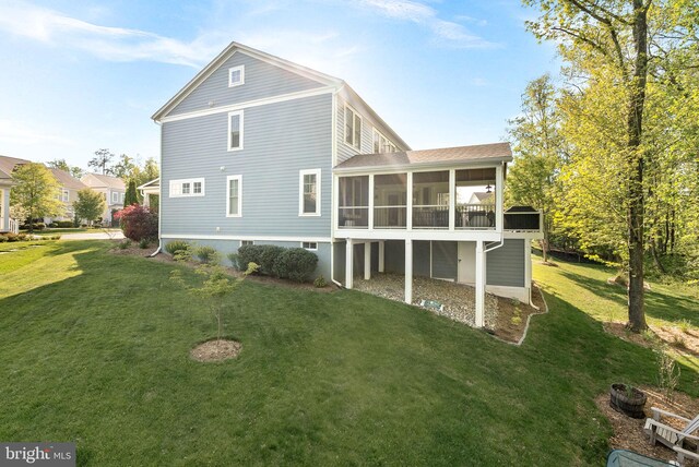 rear view of property featuring a lawn and a sunroom