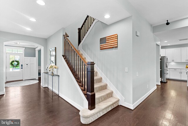 stairs featuring arched walkways, baseboards, recessed lighting, and wood finished floors