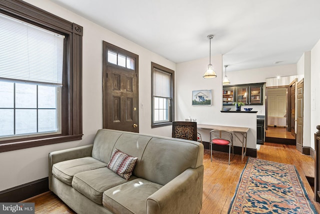 living area featuring a healthy amount of sunlight, baseboards, and light wood finished floors