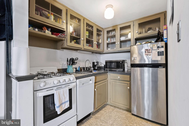 kitchen featuring open shelves, dark countertops, glass insert cabinets, a sink, and appliances with stainless steel finishes
