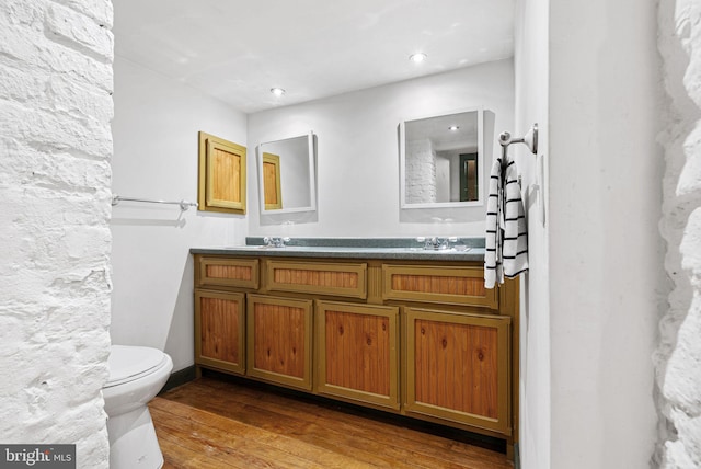 bathroom with double vanity, a sink, toilet, and hardwood / wood-style floors