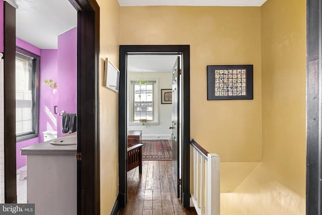 hall with baseboards, an upstairs landing, dark wood-style floors, and a wealth of natural light