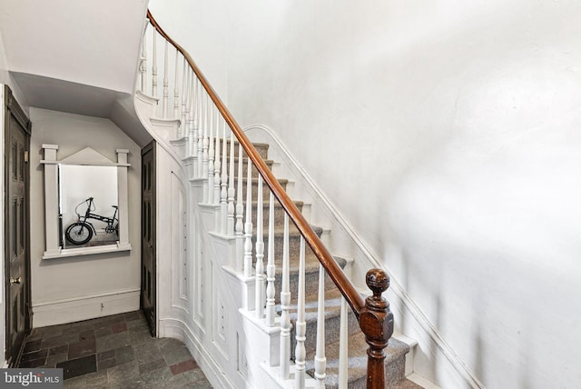 stairway featuring a high ceiling and stone finish floor