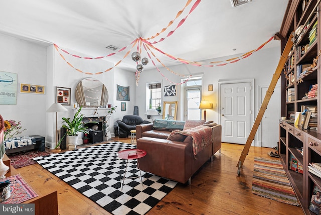 living area featuring a fireplace, wood-type flooring, and visible vents