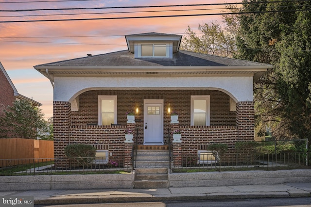 view of front of property featuring a fenced front yard, a porch, and brick siding