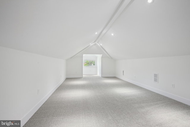 additional living space with baseboards, carpet flooring, visible vents, and vaulted ceiling with beams