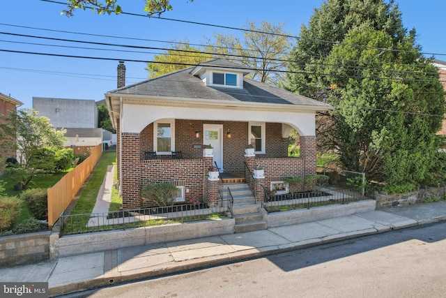view of front of home with roof with shingles, a fenced front yard, a chimney, and brick siding