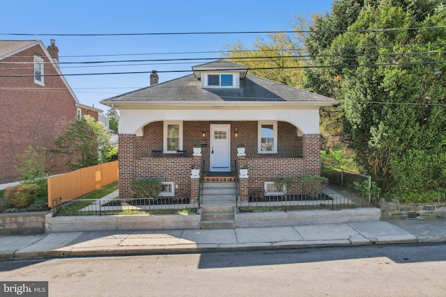 view of front of property with covered porch, brick siding, and a fenced front yard
