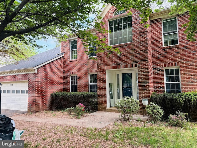 colonial inspired home with an attached garage and brick siding