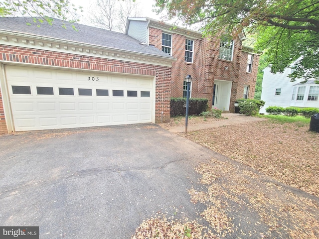 colonial house featuring brick siding, driveway, and a garage