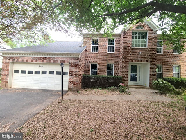 colonial inspired home featuring brick siding, a garage, and driveway