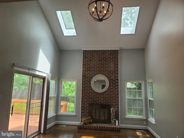 303 Saybrooke View Dr, Gaithersburg, MD 20877 - unfurnished living room with high vaulted ceiling, a skylight, wood finished floors, a chandelier, and a brick fireplace