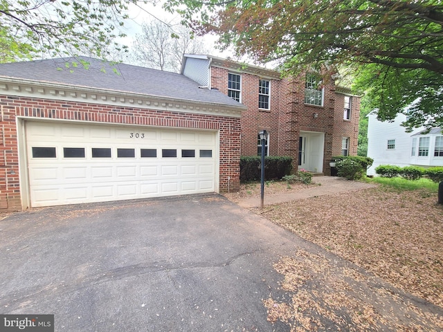 colonial-style house featuring a garage, driveway, and brick siding