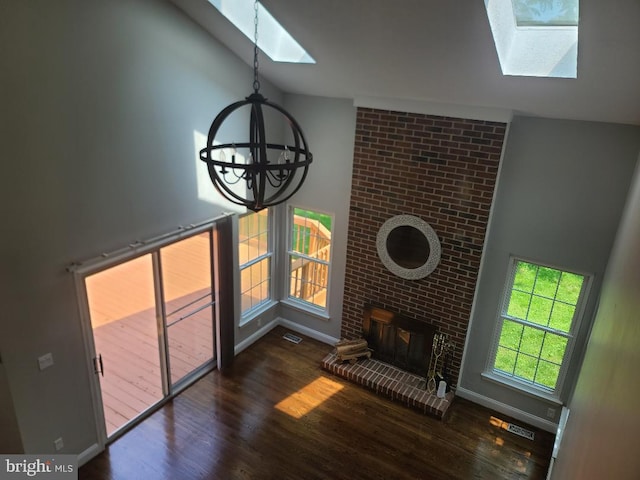 303 Saybrooke View Dr, Gaithersburg, MD 20877 - unfurnished living room with a skylight, a chandelier, vaulted ceiling, wood finished floors, and a brick fireplace