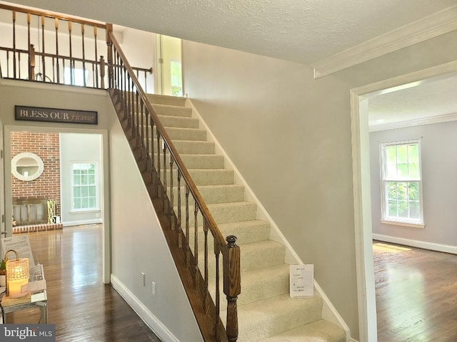 303 Saybrooke View Dr, Gaithersburg, MD 20877 - stairs featuring wood finished floors, crown molding, a textured ceiling, and a fireplace