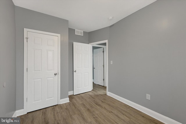 unfurnished bedroom with baseboards, visible vents, and wood finished floors